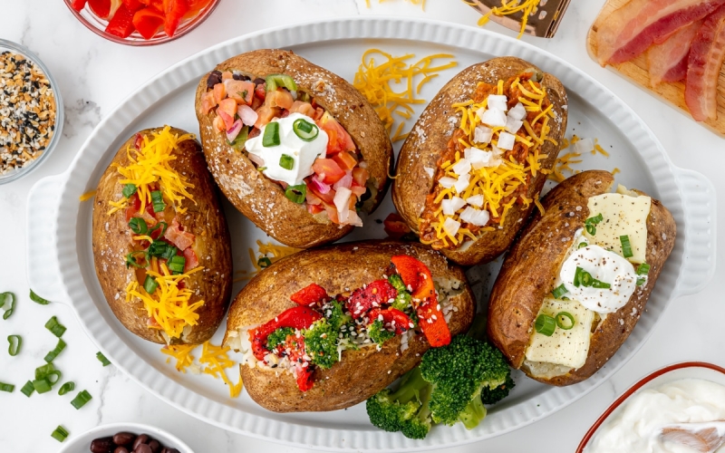overhead shot of baked potatoes with different toppings on a tray