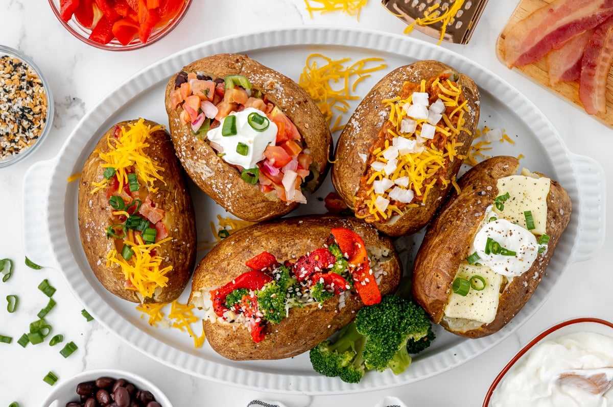 overhead shot of baked potatoes with different toppings on a tray