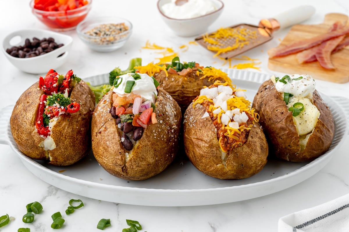 angled shot of baked potatoes with different toppings on a tray