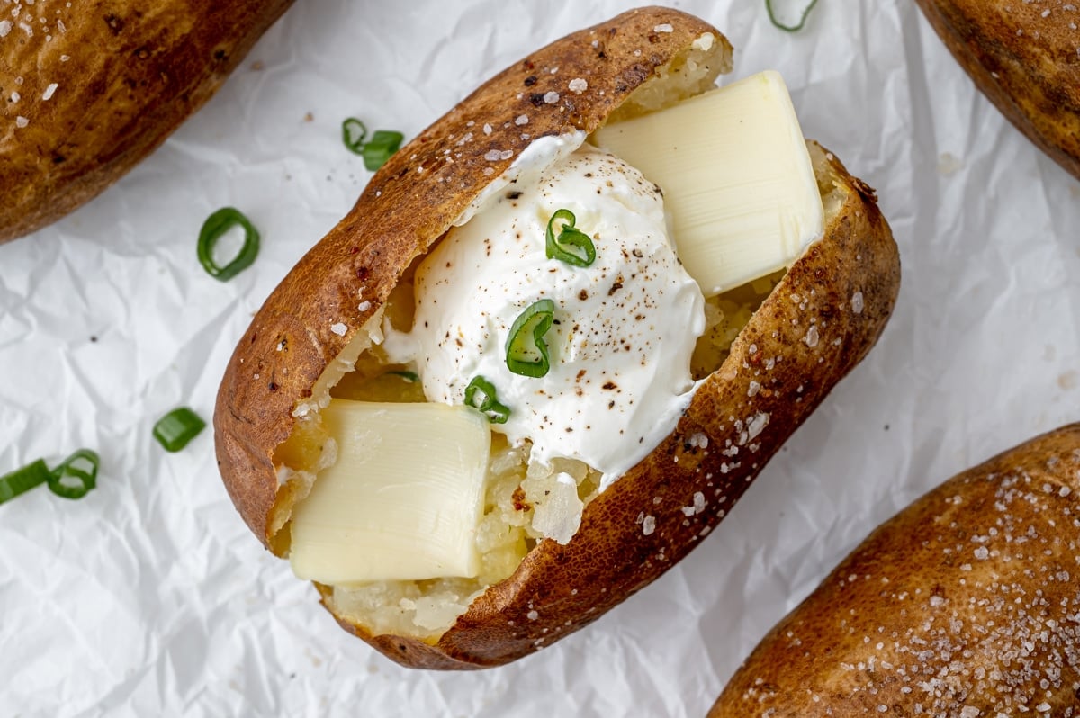 overhead shot of baked potato with sour cream and butter