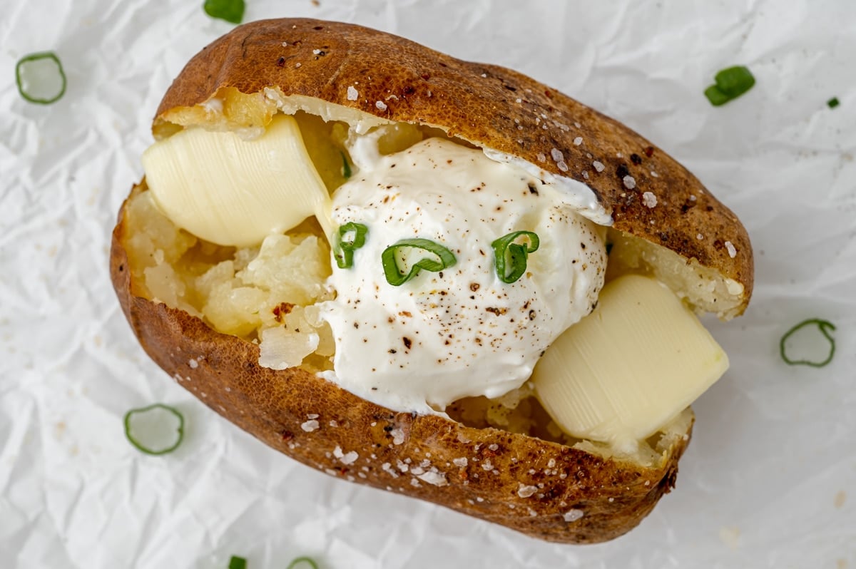 overhead shot of baked potato in oven topped with sour cream and butter