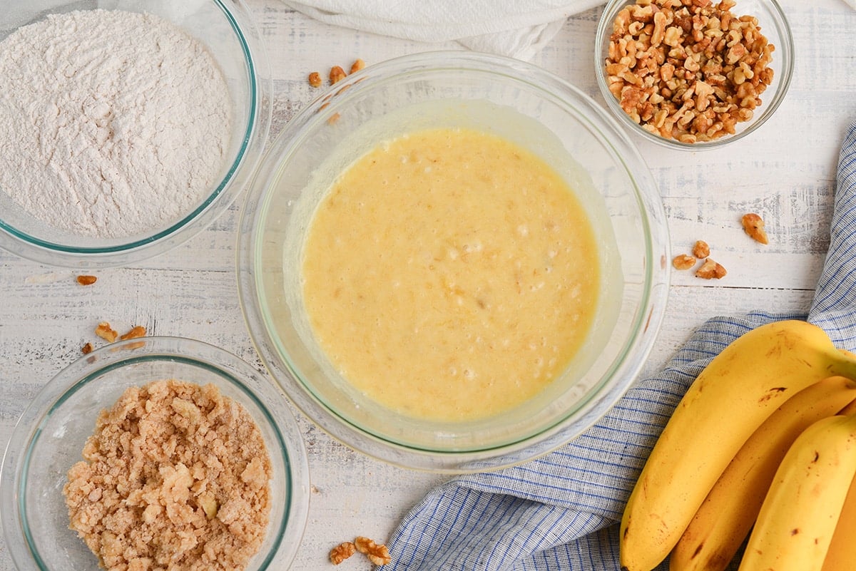 banana bread batter with streusel in a bowl and fresh bananas