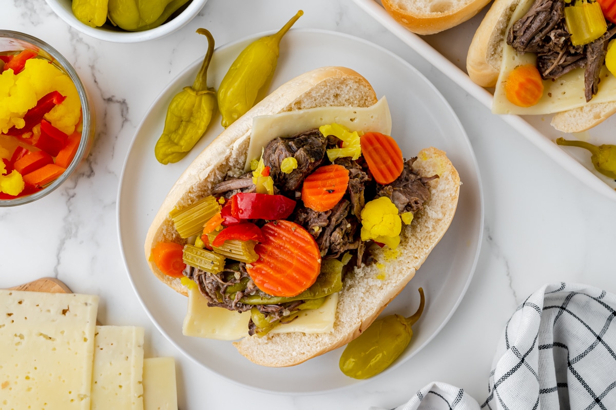 overhead shot of slow cooker italian beef sandwich on white plate