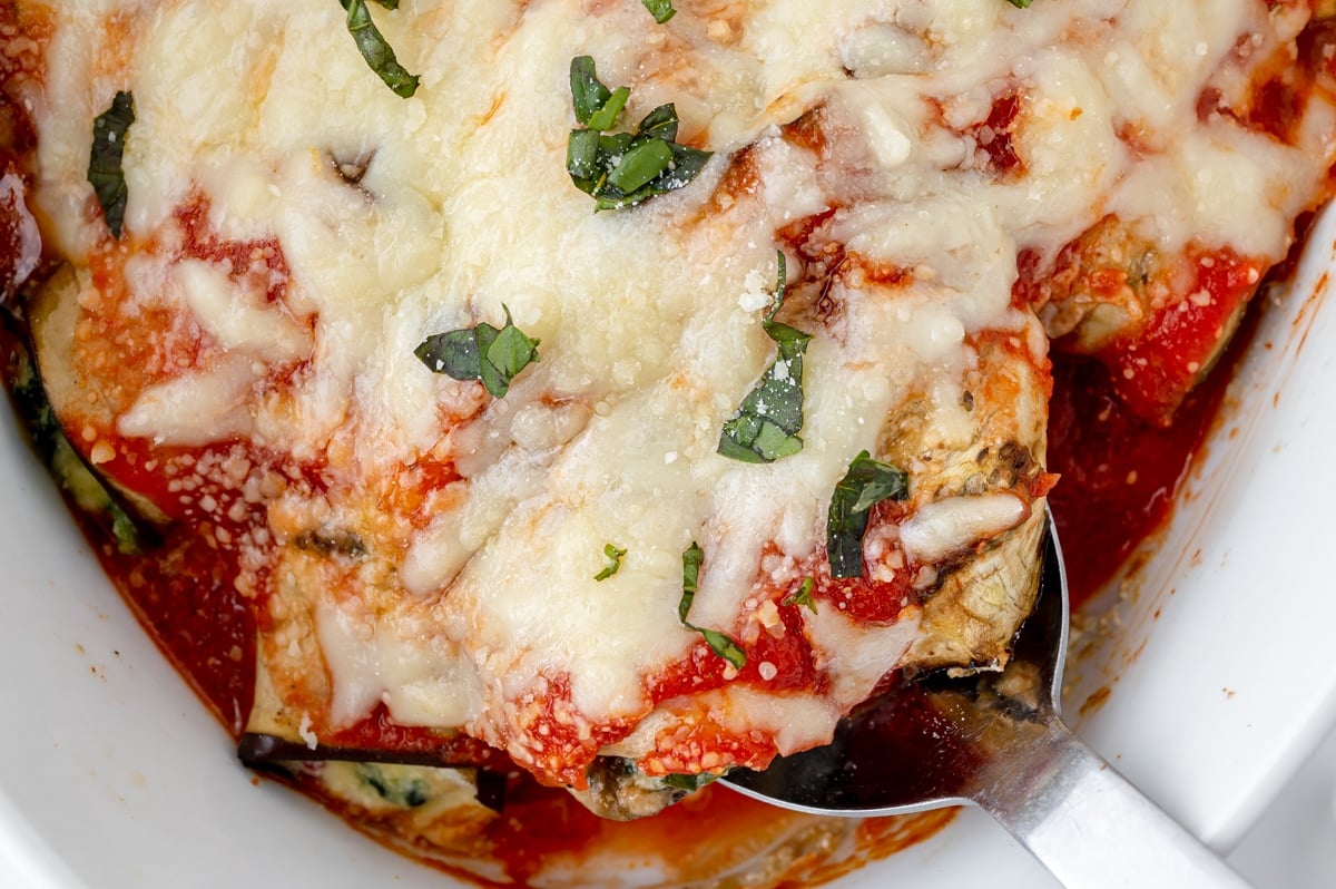 spoon in baking dish of baked eggplant