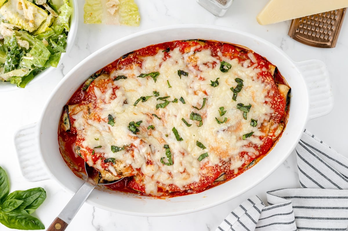 overhead shot of serving spoon in dish of eggplant rollatini