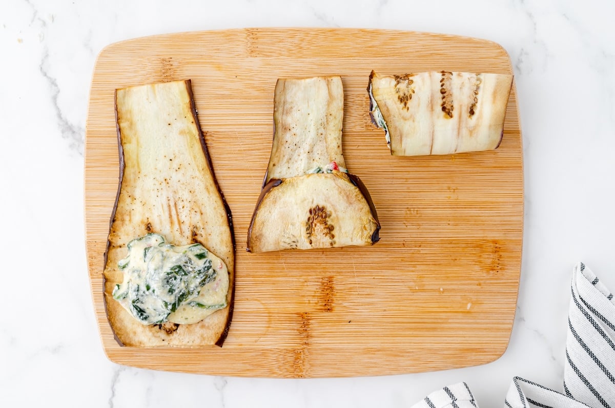 eggplant slices rolled around filling on cutting board