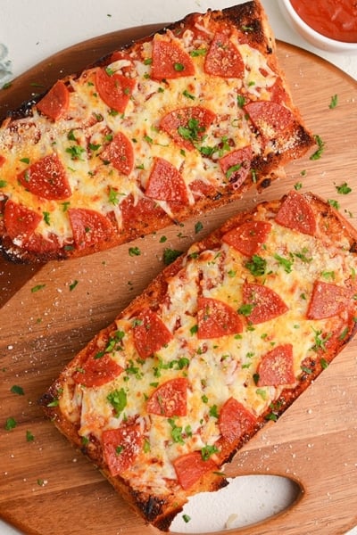 two pieces of french bread pizza on a wooden board
