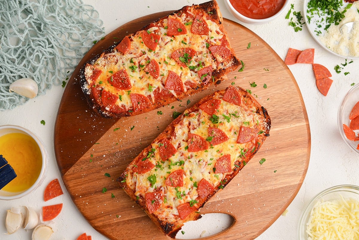 two pieces of french bread pizza on a wooden board