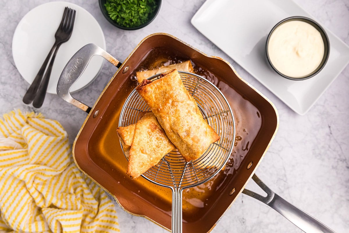 straining egg rolls out of oil