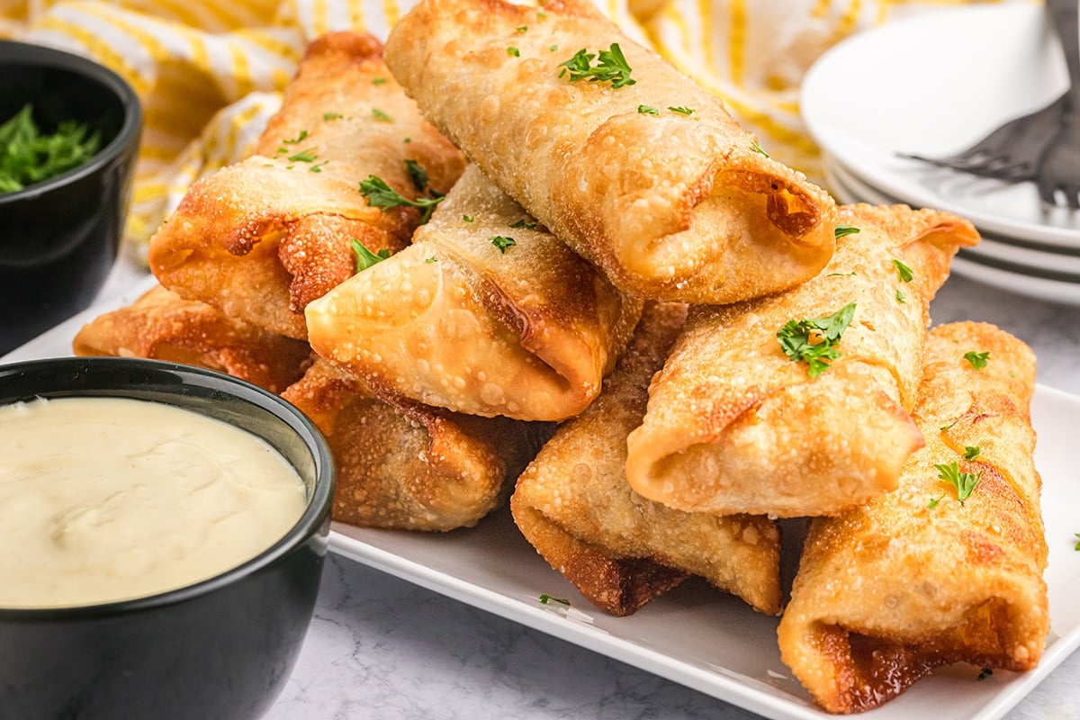 tray of egg rolls with bowl of sauce