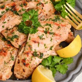 close up angled shot of chicken on a plate with lemons