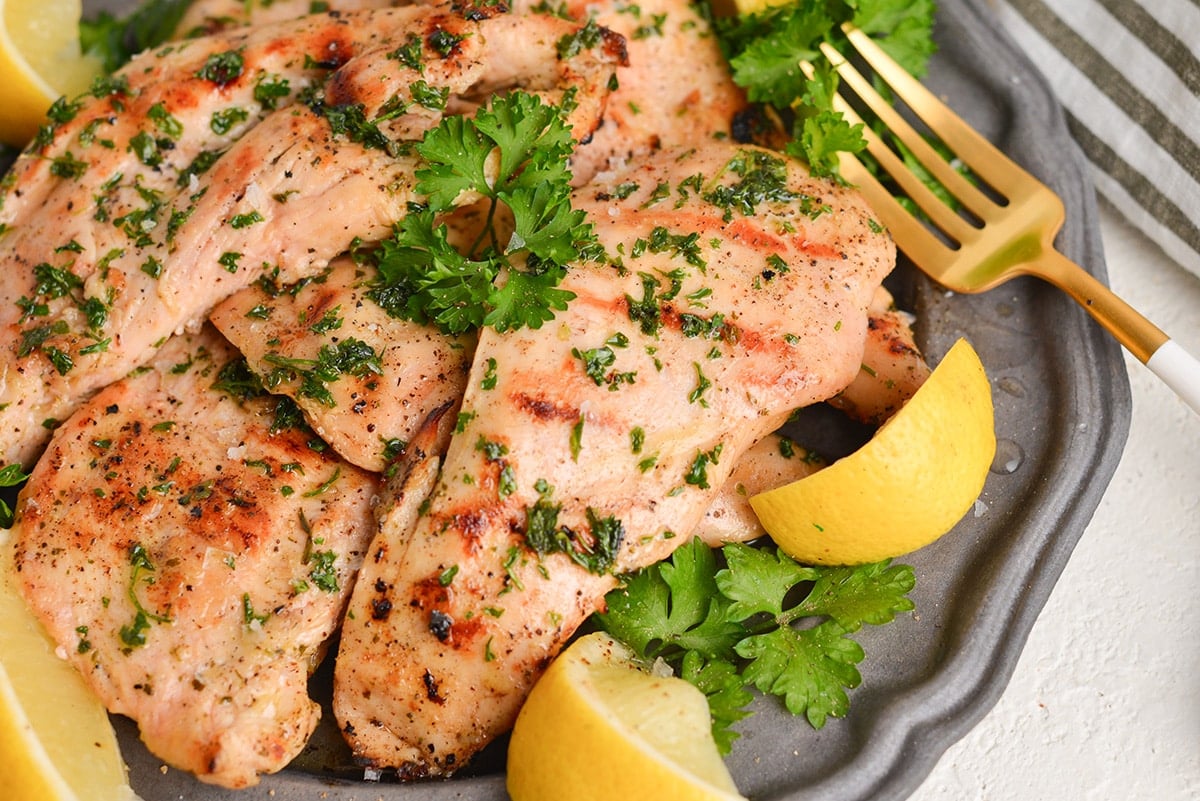 close up angled shot of chicken on a plate with lemons