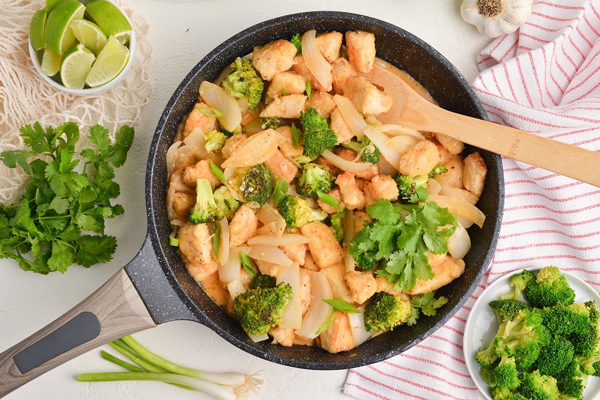overhead view of coconut chicken in a skillet with broccoli