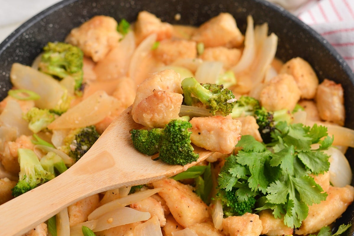 chicken chunks with broccoli on a wood spoon