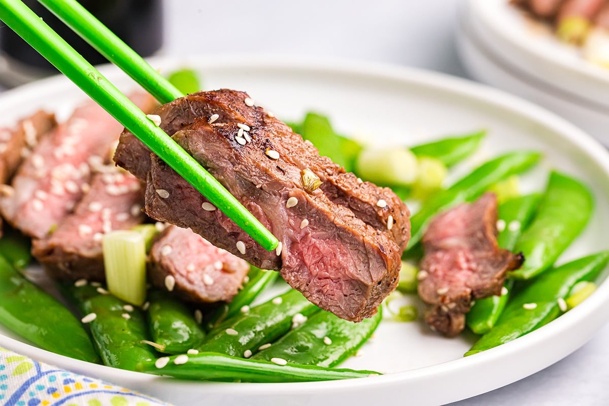 chopsticks holding two slices of asian steak