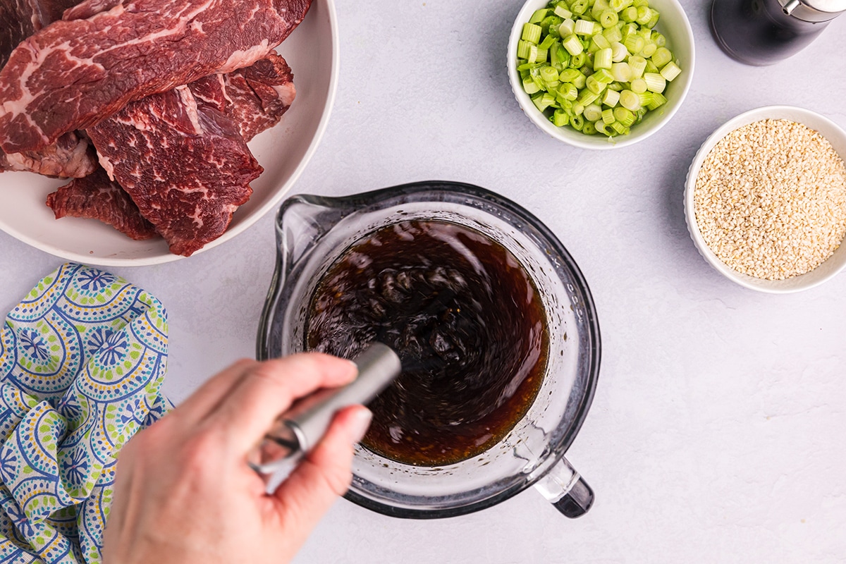 whisking asian steak marinade in measuring cup