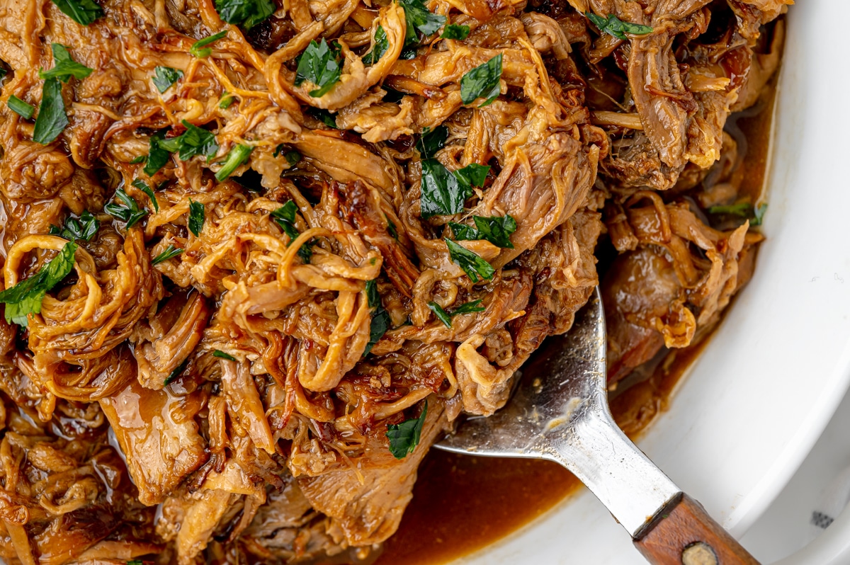 overhead shot of spoon in bowl of instant pot pulled pork