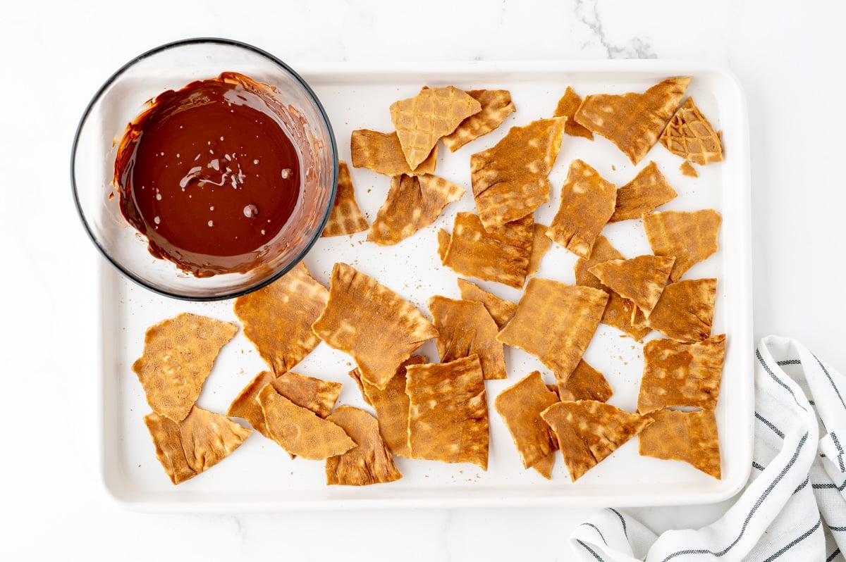 overhead shot of waffle cone pieces on sheet pan with bowl of melted chocolate