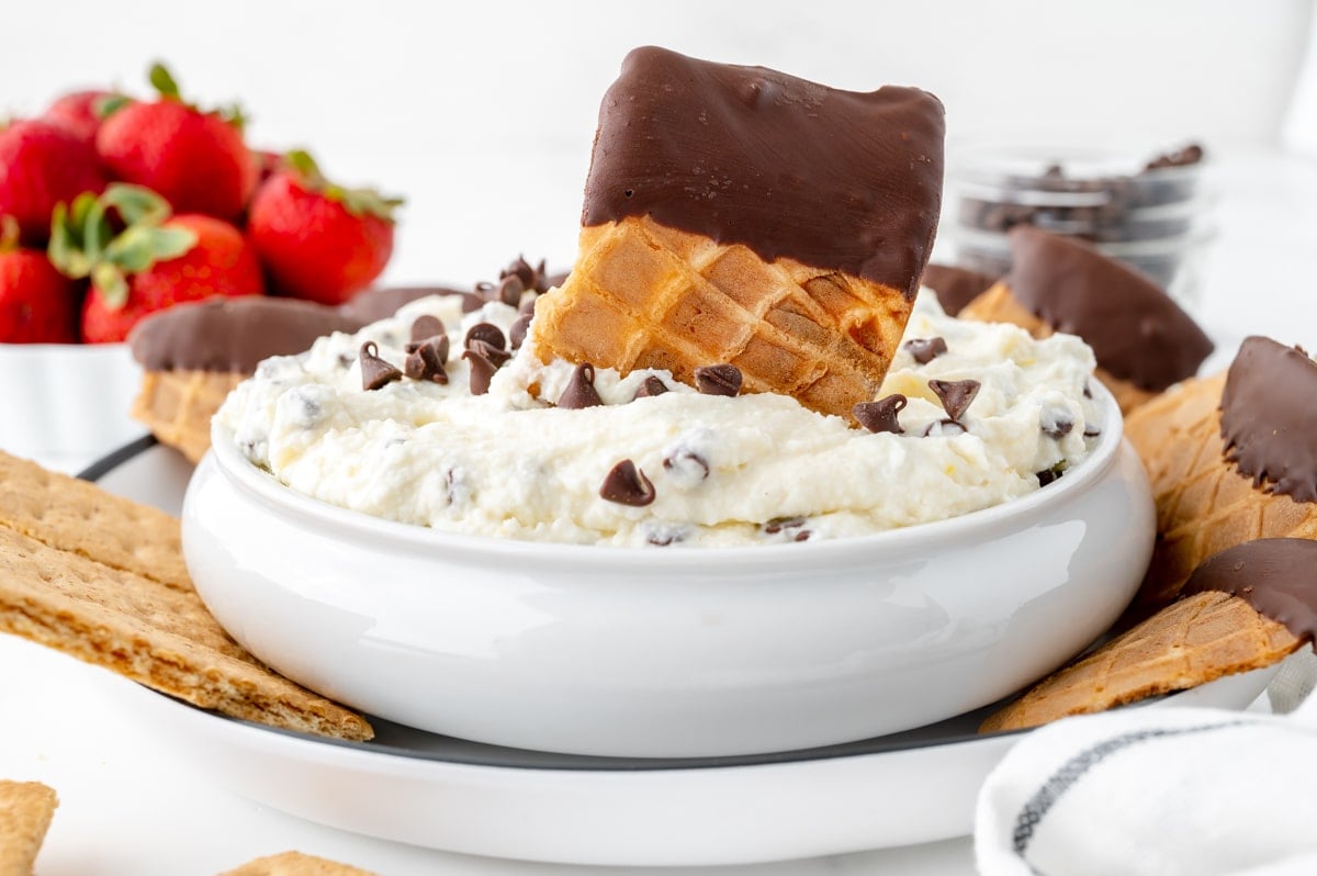 straight on shot of waffle cone piece in bowl of cannoli dip