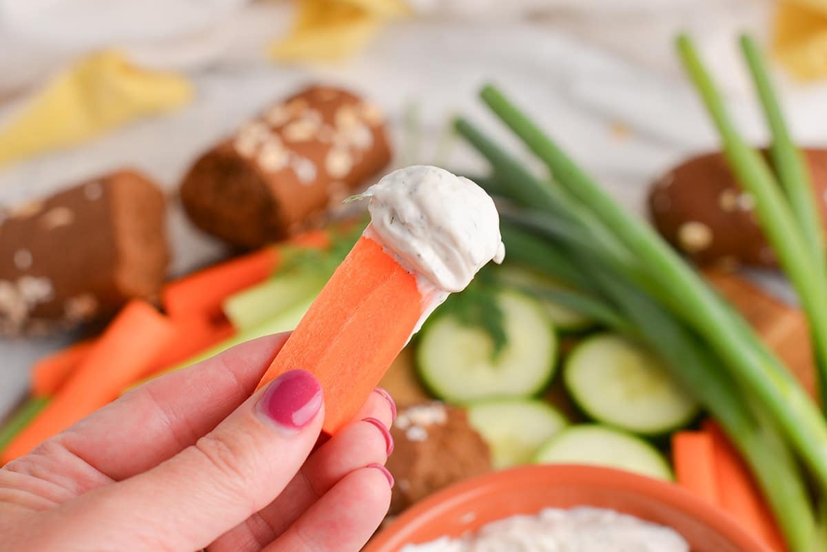 hand holding carrot with dill dip on it