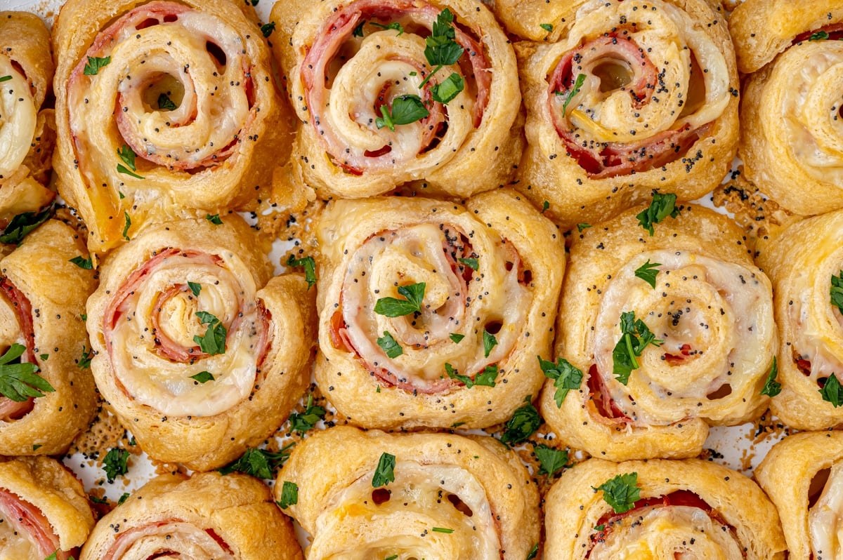 overhead close up shot of ham and cheese pinwheels in baking dish