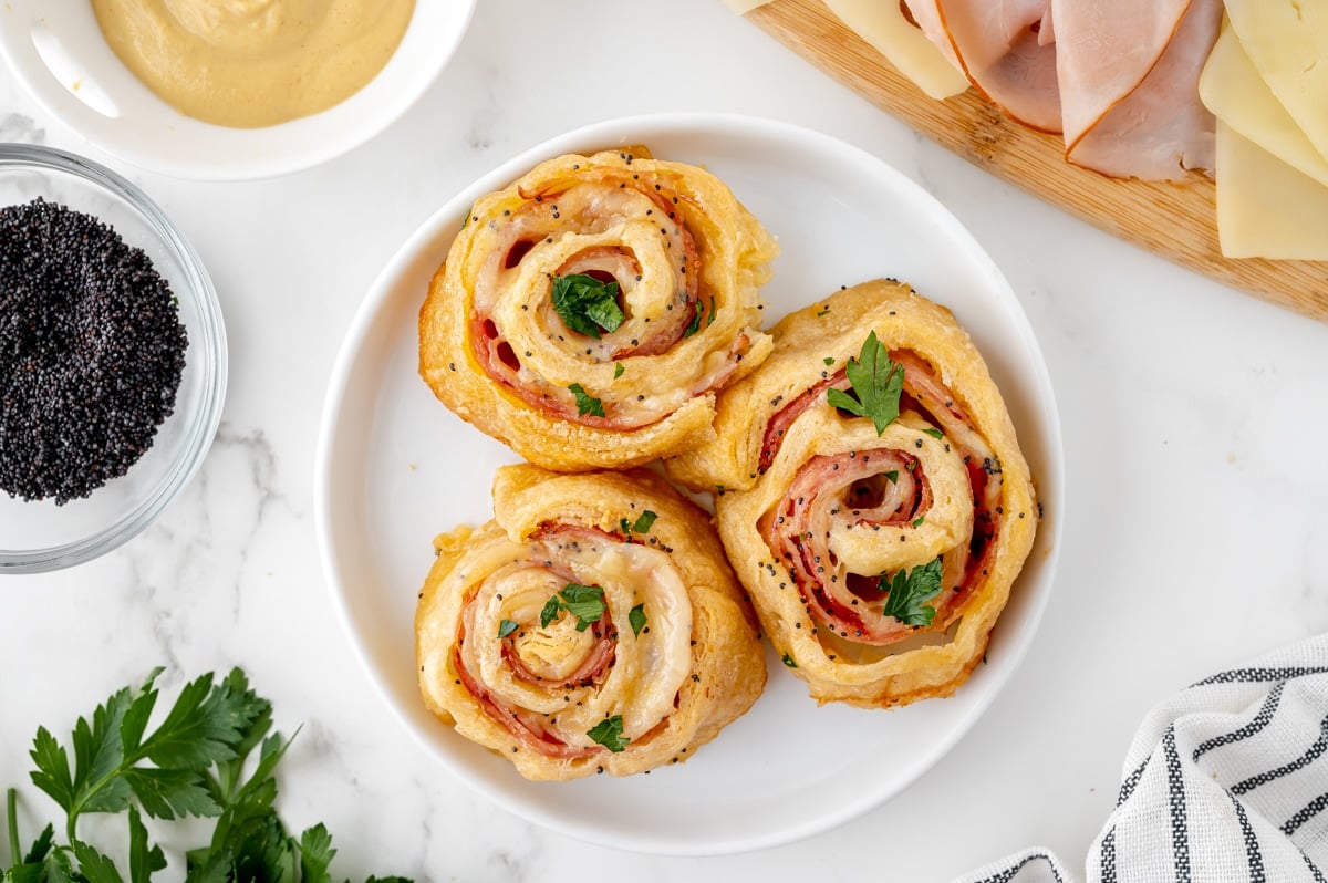 overhead shot of three ham and cheese pinwheels on a plate