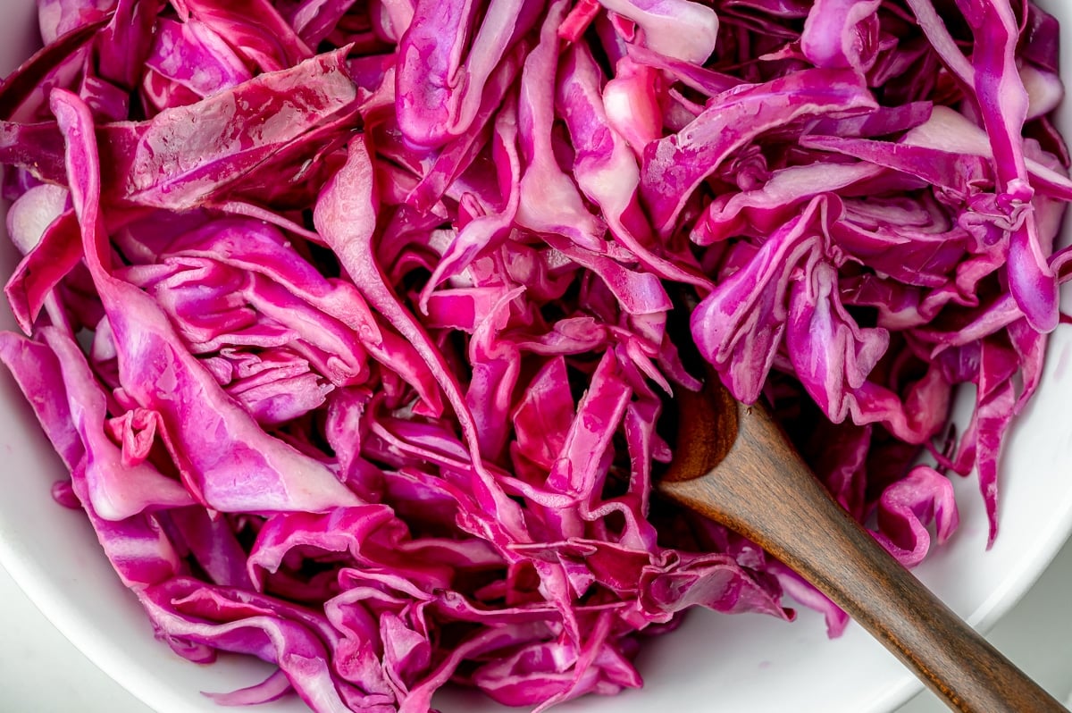 close up of wooden spoon in bowl of red cabbage slaw