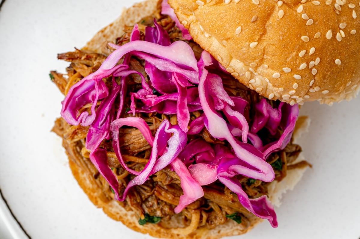 angled shot of red cabbage on pulled pork sandwich