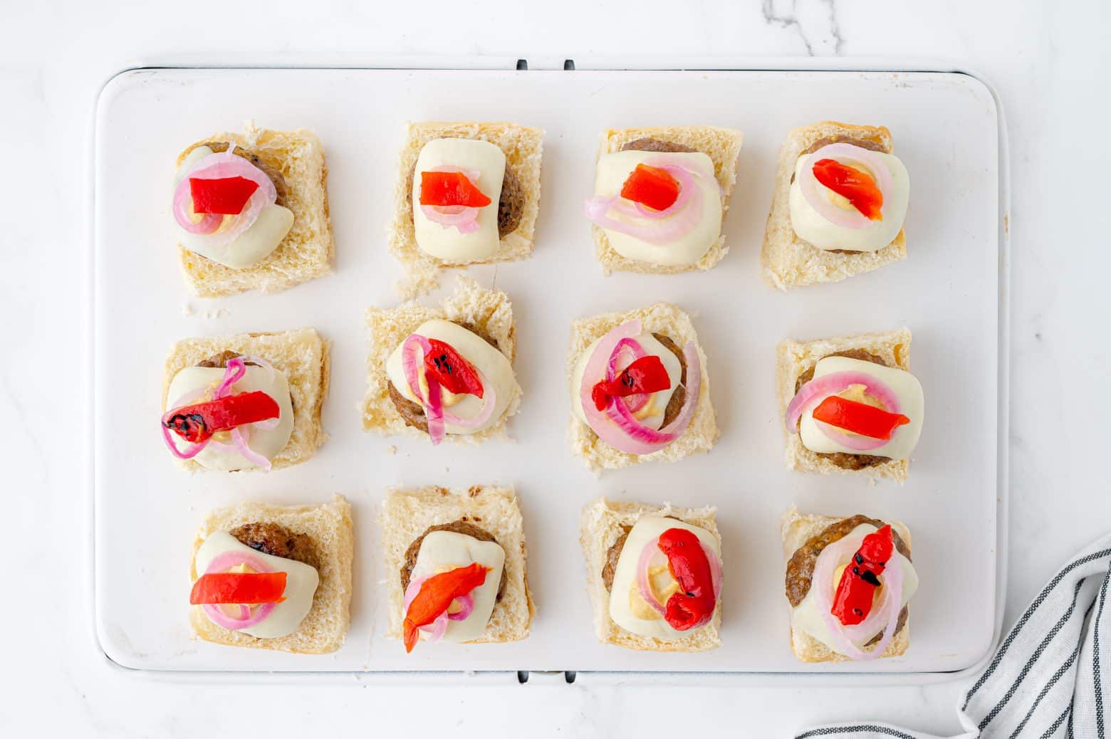 assembling sliders with pickled onions, dijon, roasted red pepper and cheese