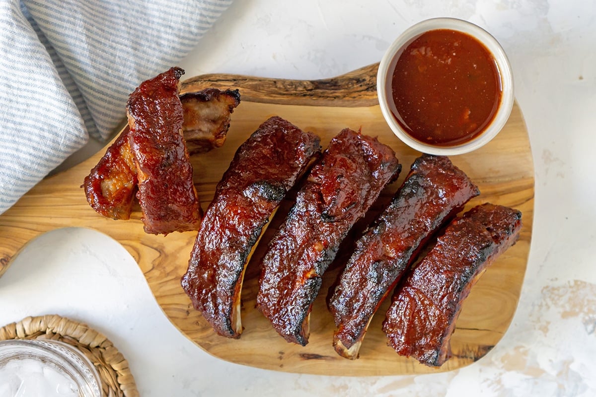 overhead shot of sliced slow cooker ribs on a cutting board with sauce