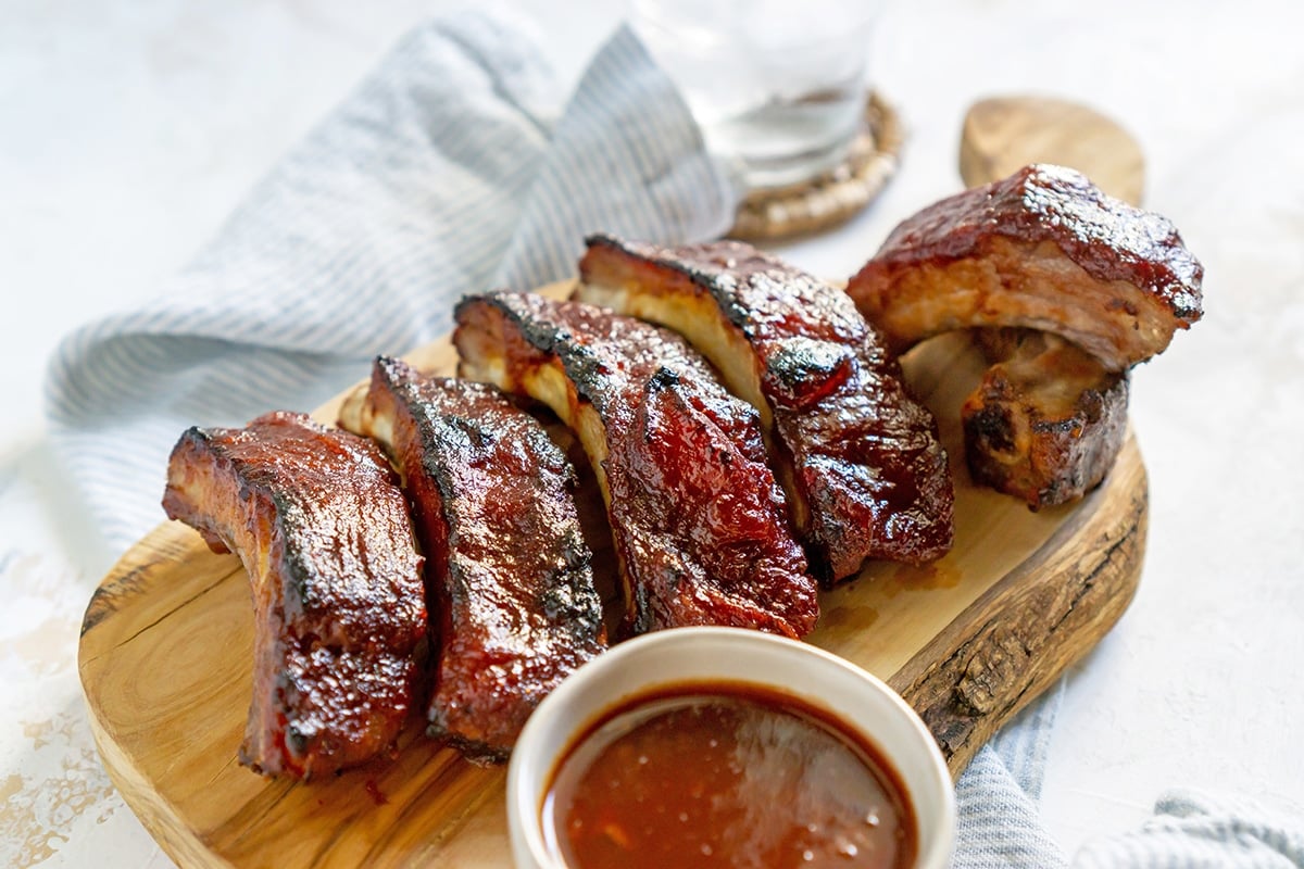 angled shot of slow cooker ribs on a wooden cutting board
