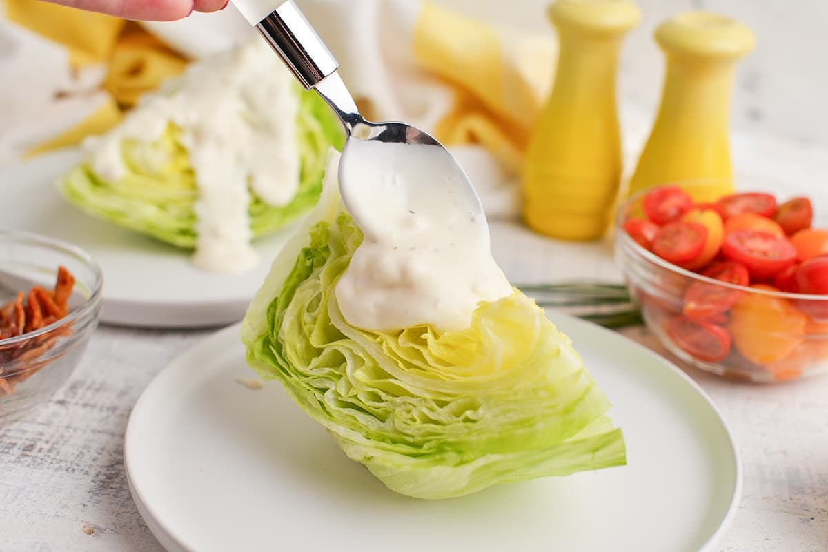 spoon adding dressing to lettuce wedge