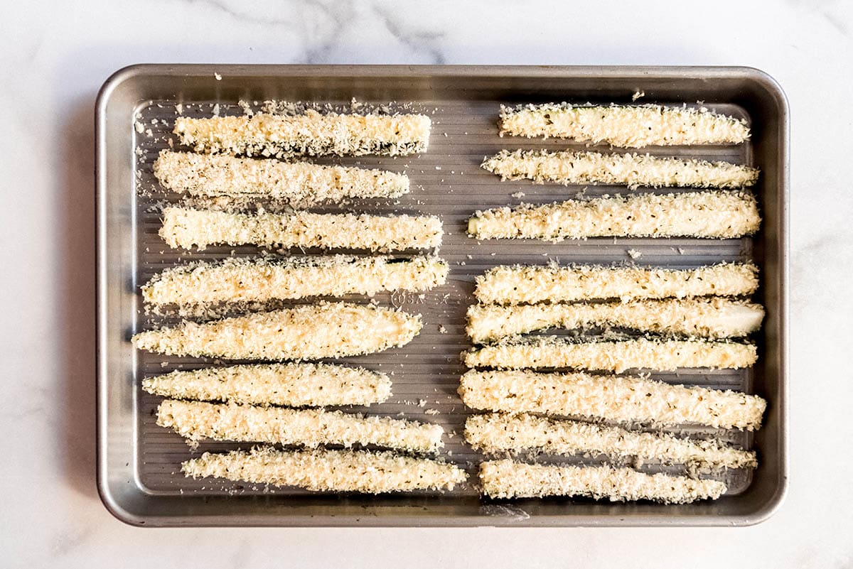 coated zucchini fries on a baking sheet