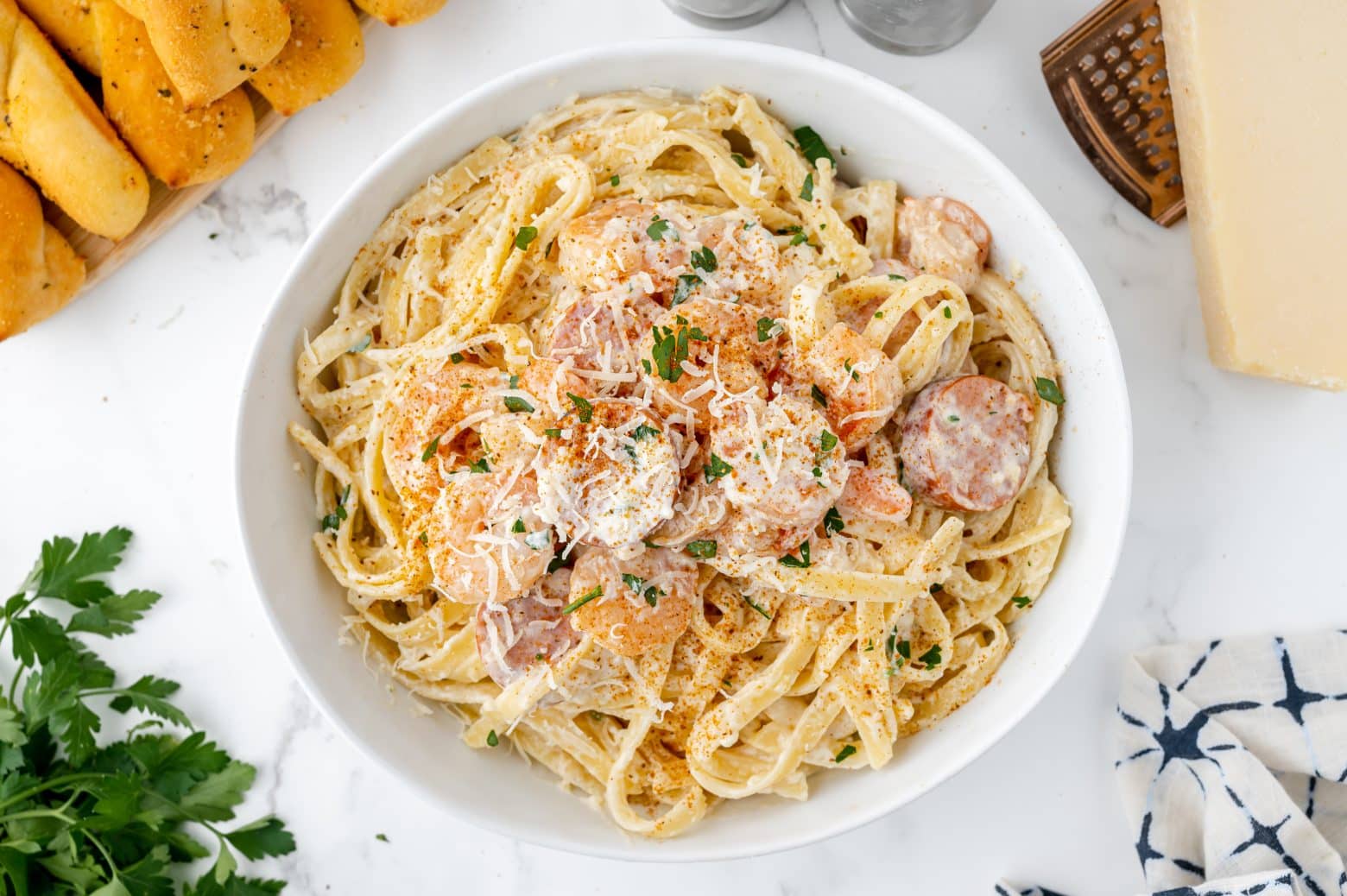 cajun shrimp alfredo in a white serving bowl with seasoning and shredded cheese