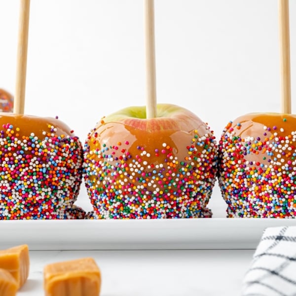 three caramel apples on a tray