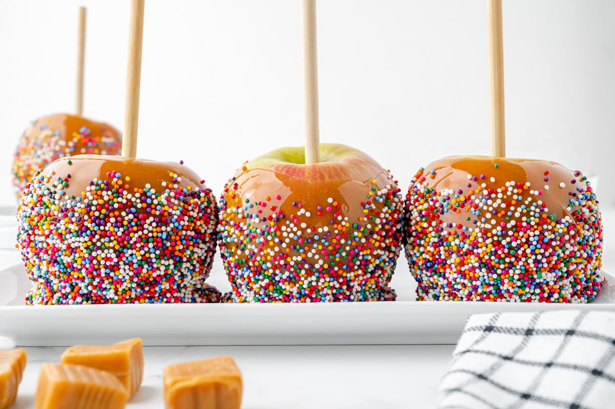 three caramel apples on a tray