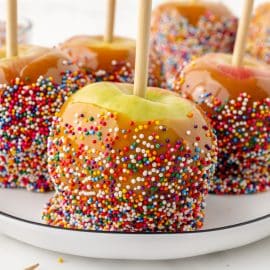 four caramel apples on a plate