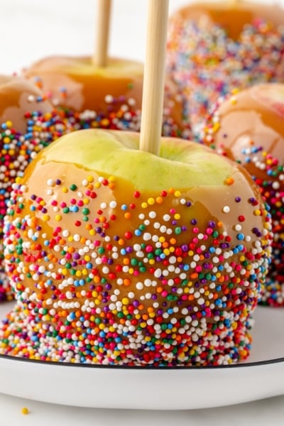 four caramel apples on a plate