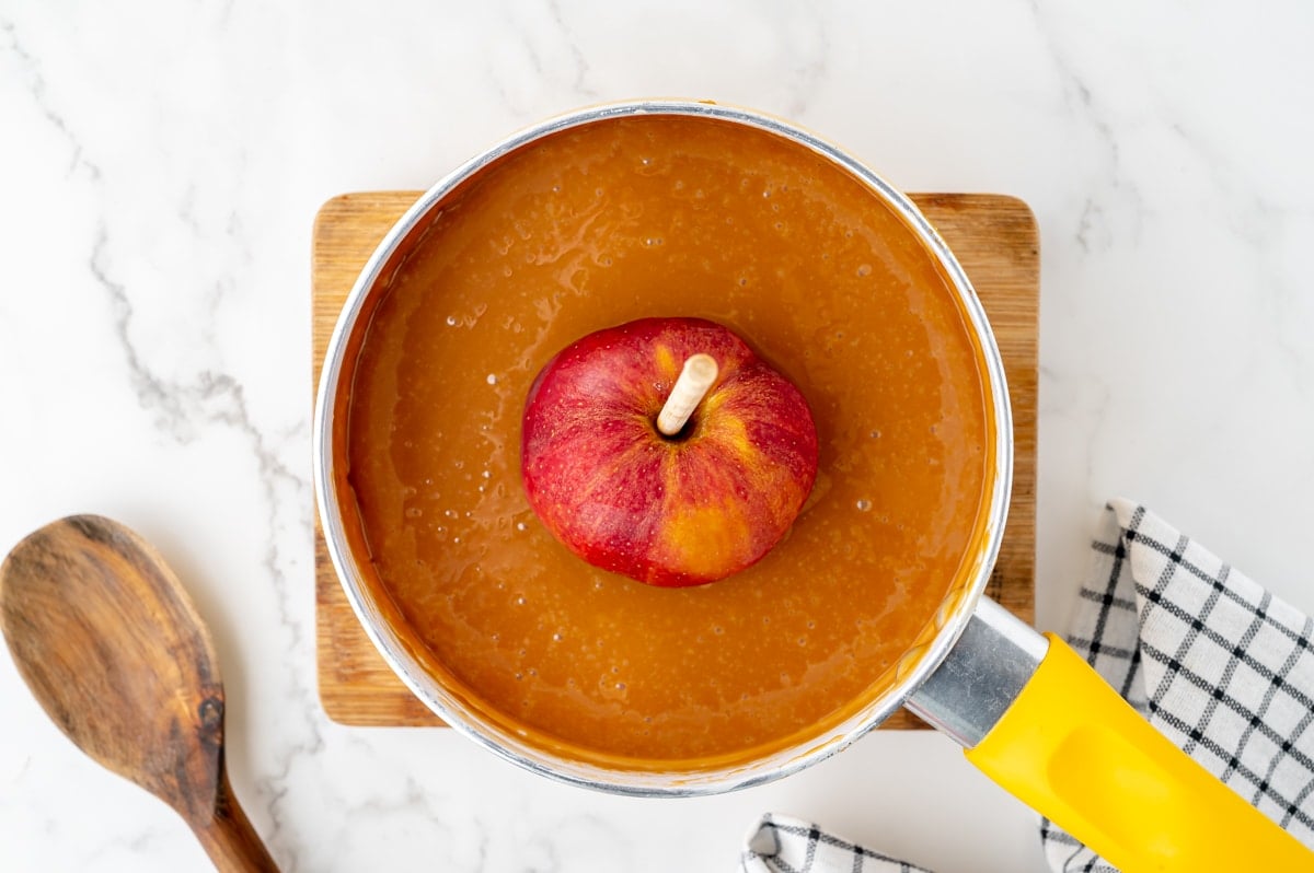 apple in pot of melted caramel