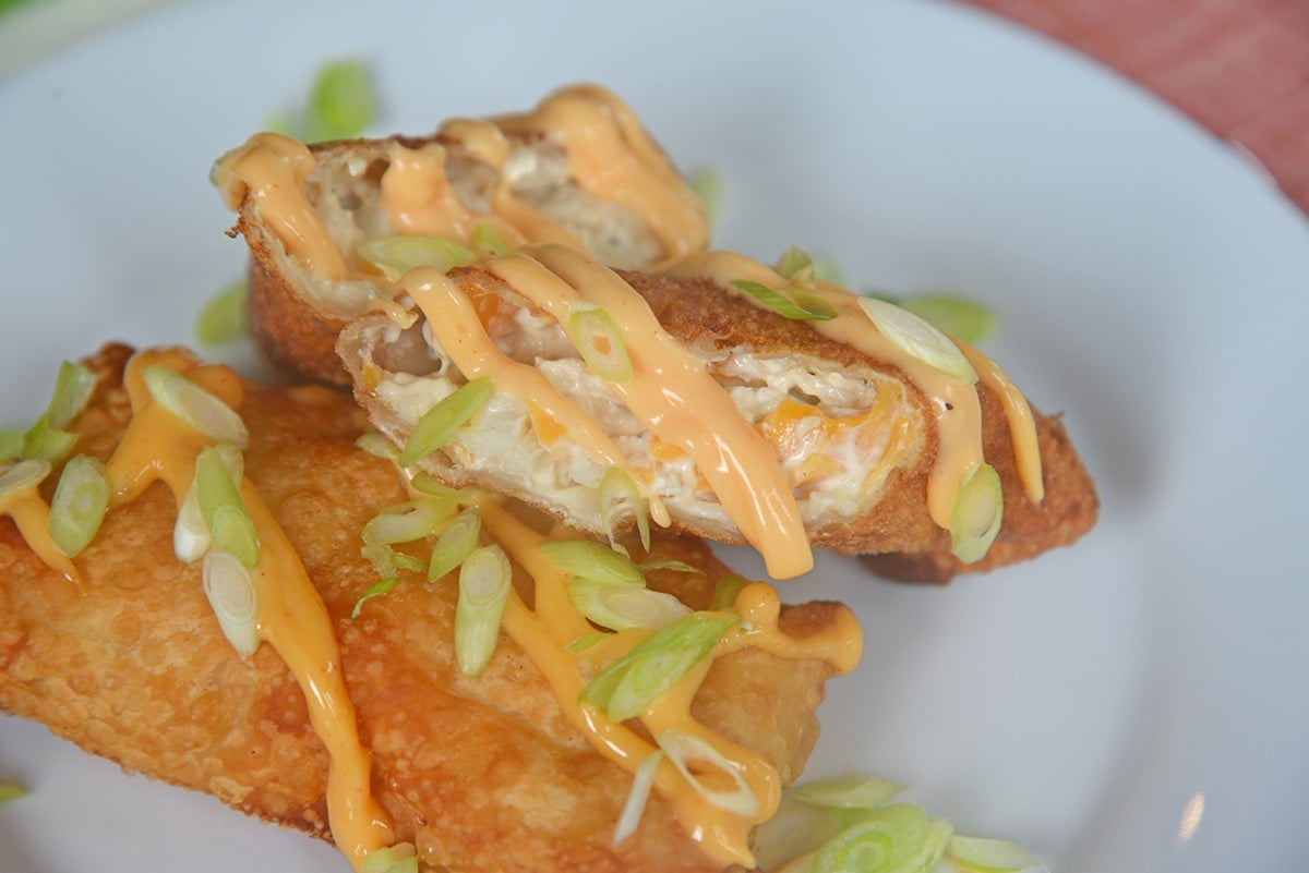 close up of crab cake egg rolls topped with sauce