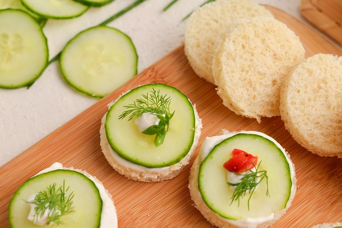 angled shot of cucumber sandwiches on board with slices of bread