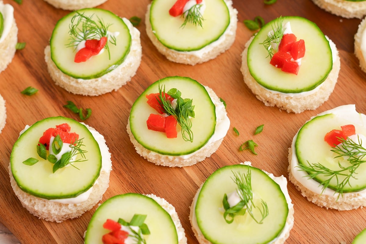 close up angled shot of cucumber sandwiches on a board