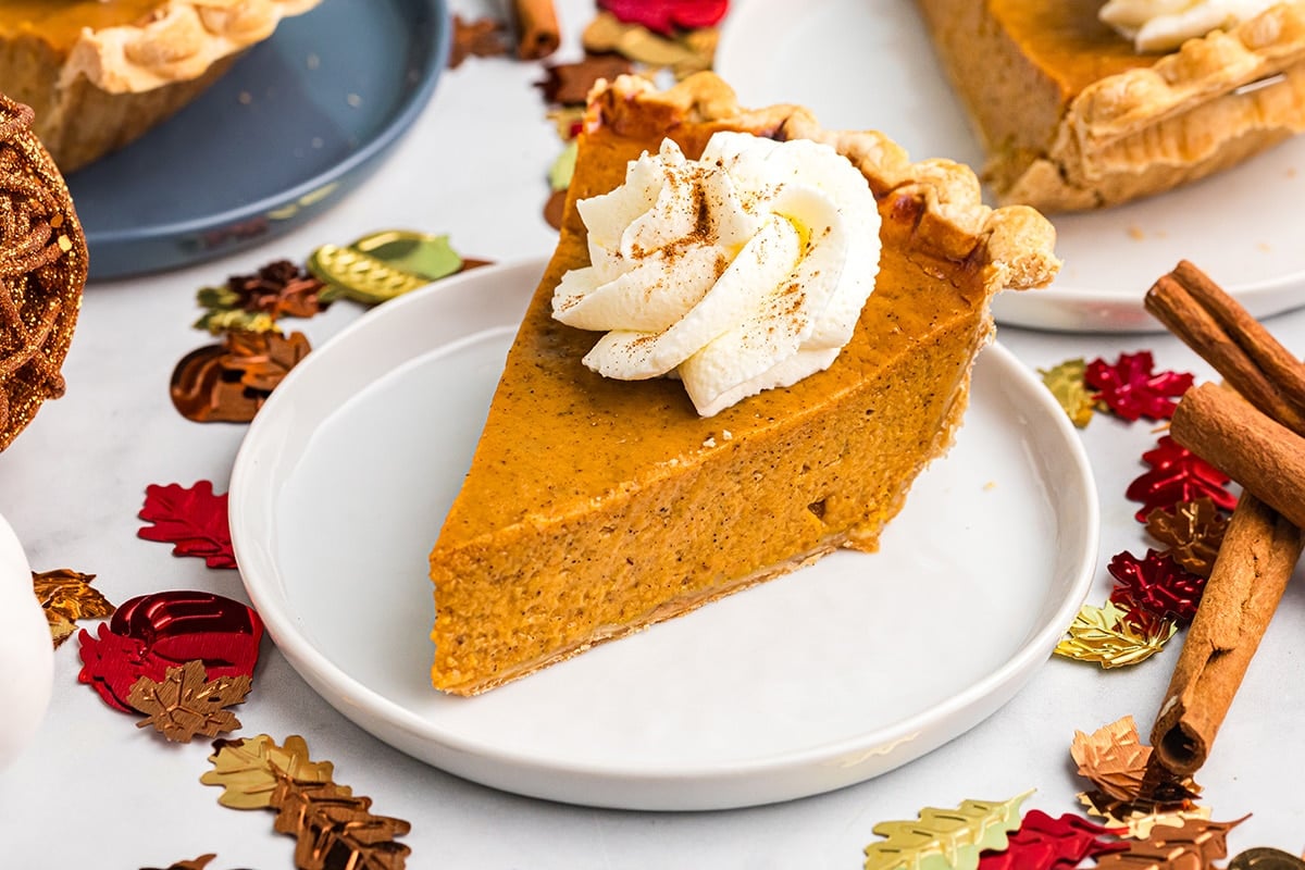 angled shot of slice of pie topped with whipped cream on plate