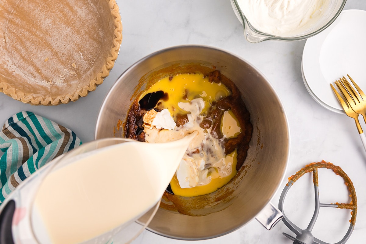 evaporated milk poured into pumpkin pie filling