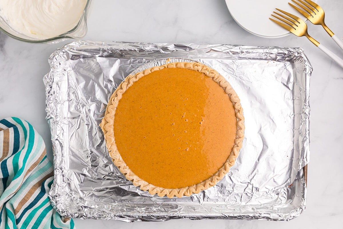 pumpkin pie filling in crust on baking sheet