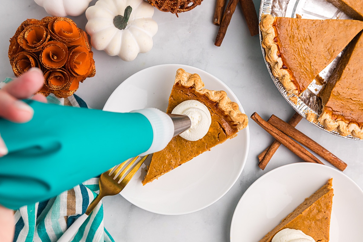 bag piping whipped cream on slice of pie