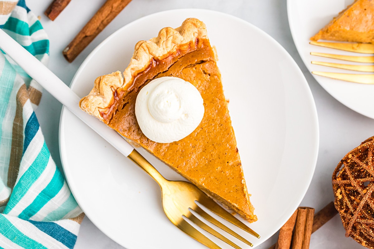 overhead shot of slice of pumpkin pie on plate with whipped cream