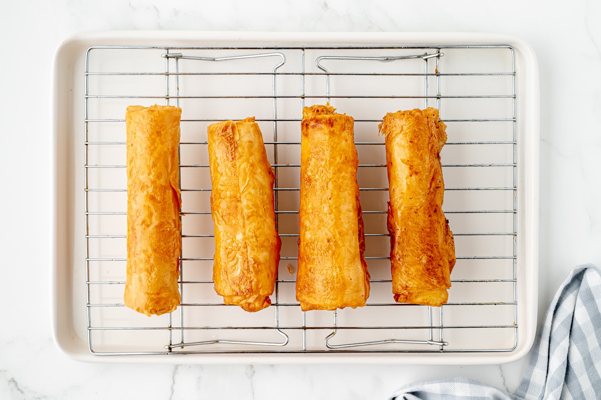 overhead shot of 4 fried cheesecake rolls on a cooling rack