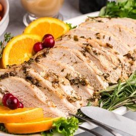 angled shot of platter of roast turkey breast with oranges and cranberries