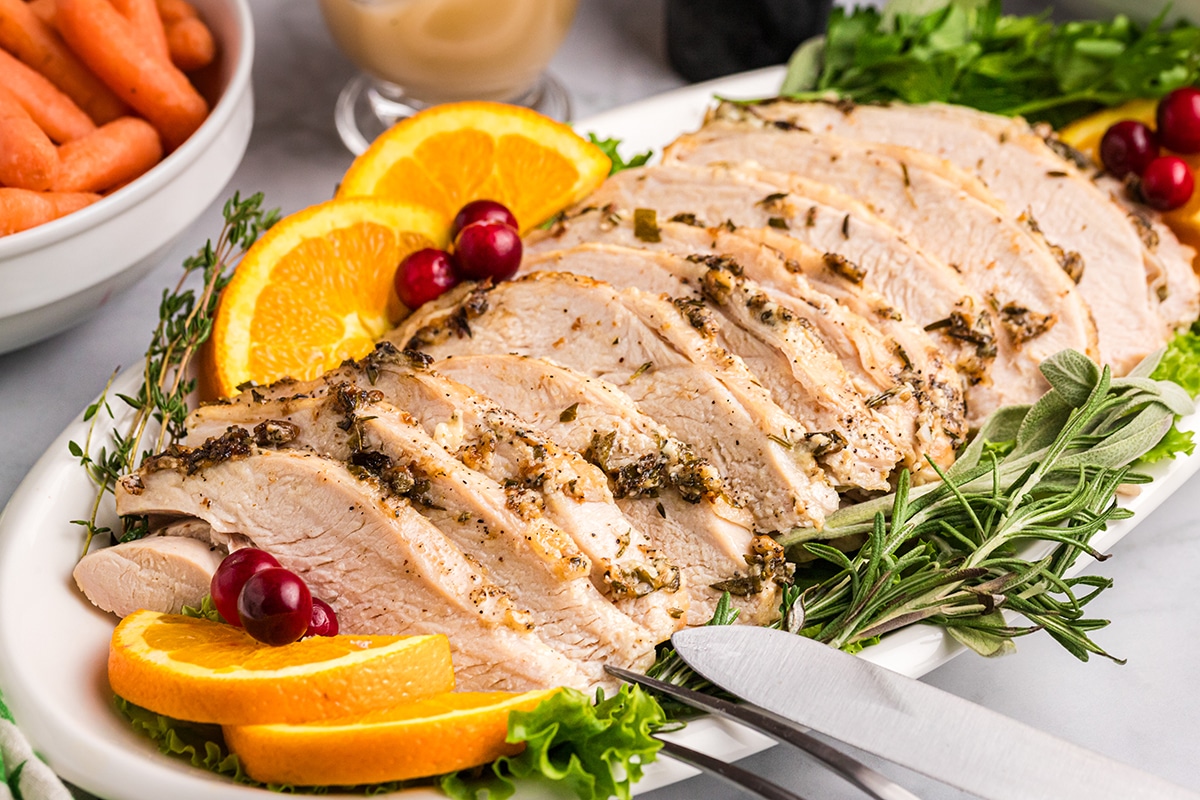 angled shot of platter of roast turkey breast with oranges and cranberries